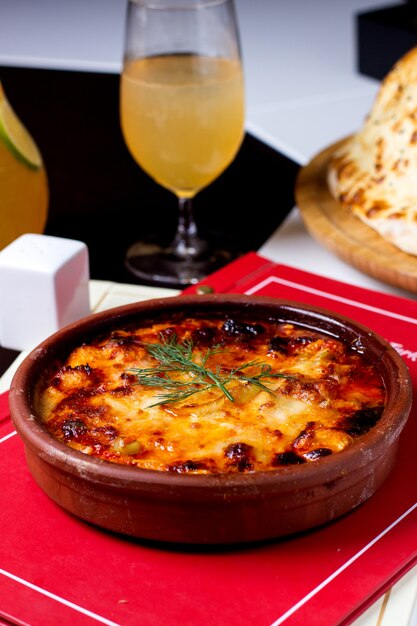 Une casserole de poterie avec plat sauté recouvert de fromage fondu