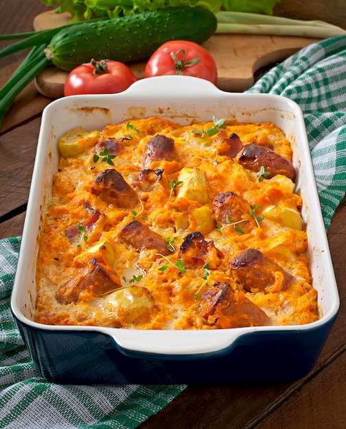 Casserole avec saucisse, bacon et pommes dans une sauce au potiron et au fromage