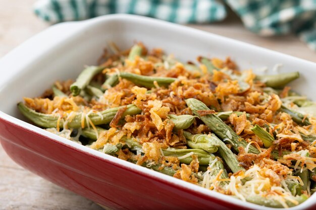 Une casserole traditionnelle de haricots verts garnie d'oignons frits et de crème de champignons sur une table en bois