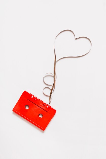 Cassette audio rouge avec bande en forme de coeur emmêlé sur fond blanc