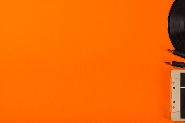 Cassette et disque vinyle sur un fond orange