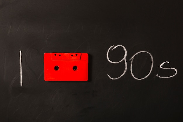 Cassette rouge avec années 1990 écrit sur tableau noir