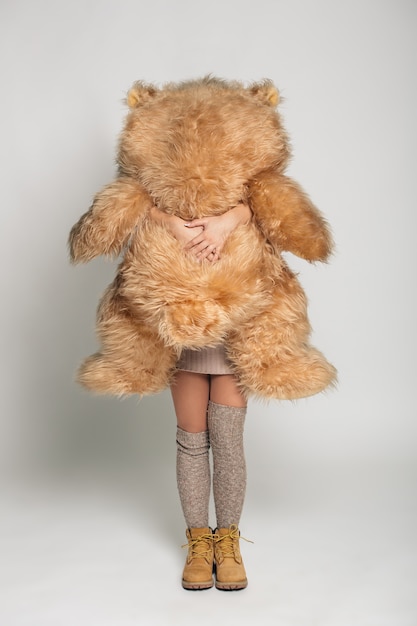 Photo gratuite casual jeune femme souriante en vêtements tricotés tenant un gros ours en peluche doux