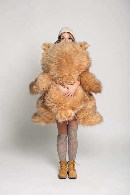 Casual jeune femme souriante en vêtements tricotés tenant un gros ours en peluche doux