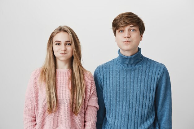 Caucasian couple looking at camera soufflant leurs joues avec une expression de visage positive