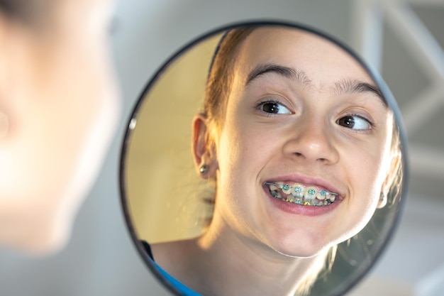 Photo gratuite caucasian preteen girl avec des accolades sur ses dents en regardant le miroir
