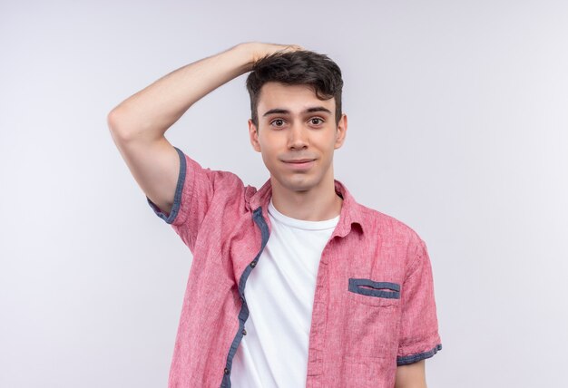 Caucasian young man wearing pink shirt a mis sa main sur la tête sur un mur blanc isolé