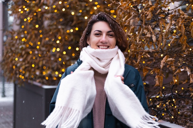 Caucasien femme souriante heureuse appréciant la neige et l'hiver, portant une écharpe chaude