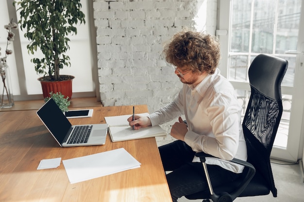 Photo gratuite caucasien jeune homme en tenue de travail travaillant dans un emploi de bureau étudiant en ligne