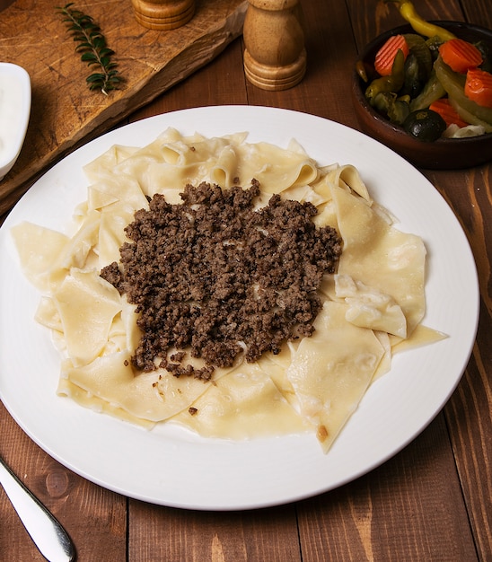 Caucasien traditionnel foor khingal, khinkali. Pâtes caucasiennes avec de la viande dans une assiette blanche sur une table en bois.