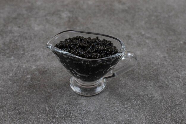 Caviar frais noir dans un bol en verre sur une surface grise