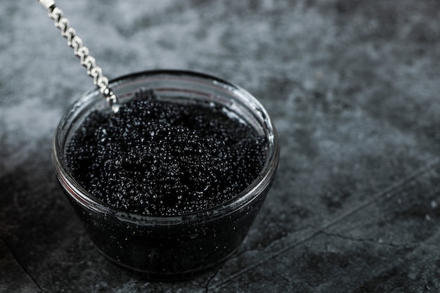 Caviar noir dans un petit pot avec une cuillère à l'intérieur