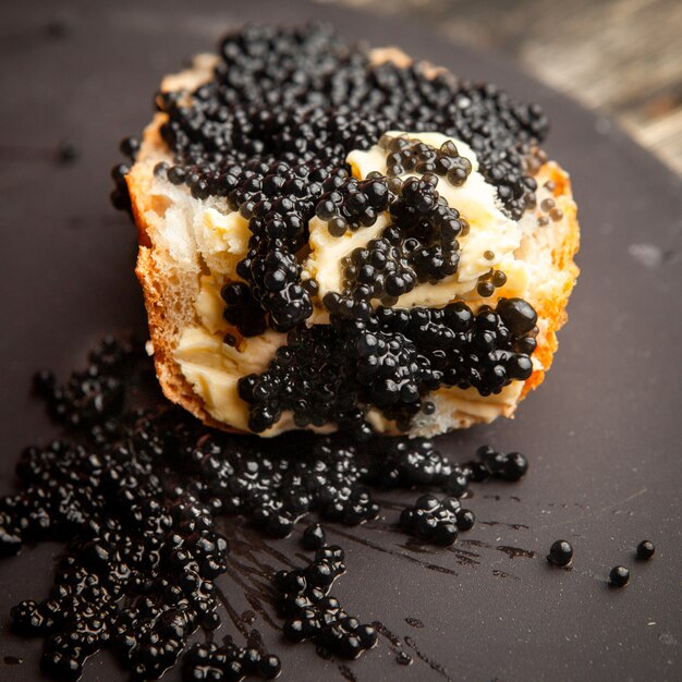 Caviar noir vue grand angle sur un pain et fond sombre