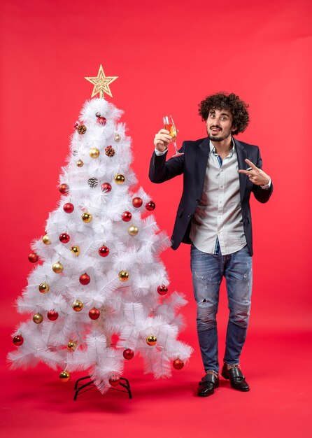 Célébration du nouvel an avec heureux jeune homme tenant un verre de vin faisant le geste de la victoire