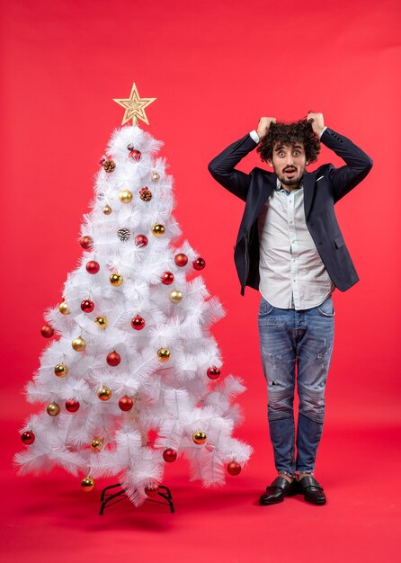 Célébration de Noël avec un jeune homme barbu épuisé de tout et se sentir extrêmement nerveux debout près de l'arbre de Noël