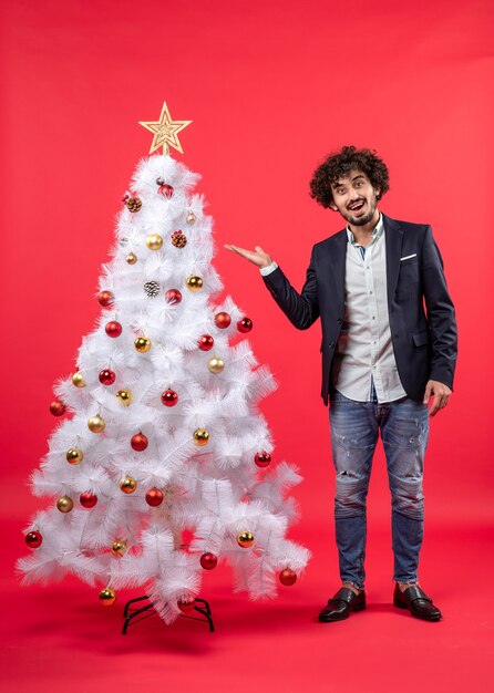 Célébration de Noël avec jeune homme barbu pointant l'arbre de Noël