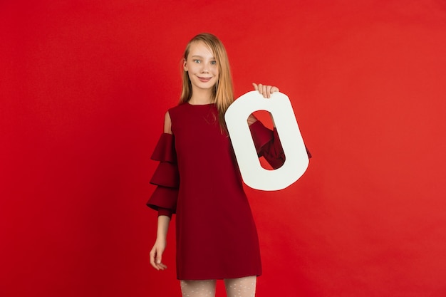 Célébration de la Saint-Valentin, heureuse, jolie fille caucasienne tenant une lettre sur fond de studio rouge.