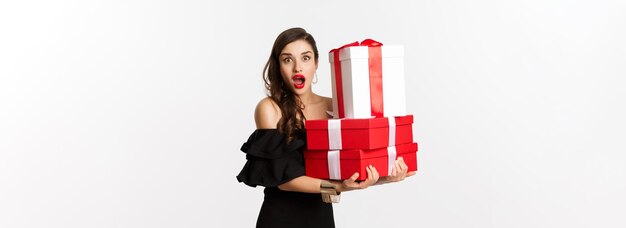 Célébration et vacances de Noël concept belle femme en robe noire tenant des cadeaux et à la recherche