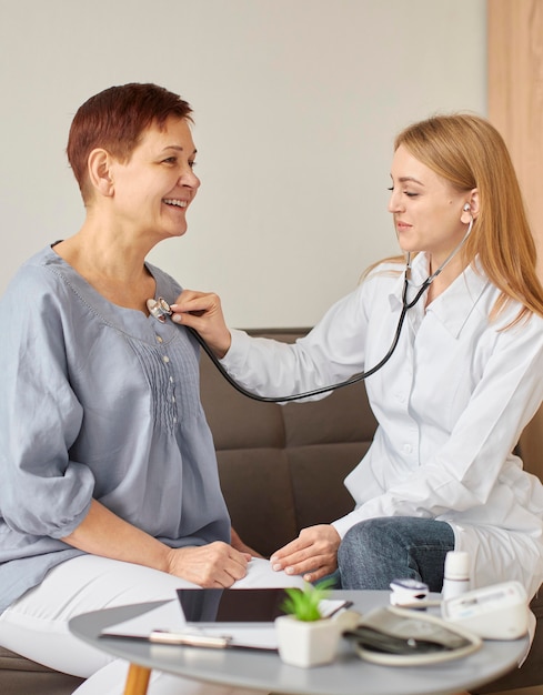 Centre de récupération Covid femme médecin vérifiant le rythme cardiaque d'un patient âgé avec un stéthoscope