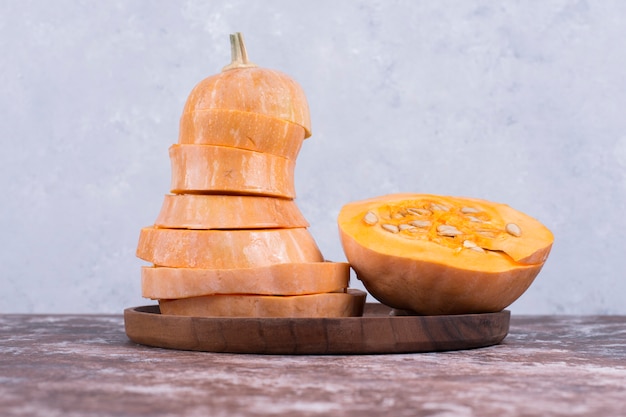 Photo gratuite cercle de citrouille en tranches dans un plateau en bois au milieu, vue latérale