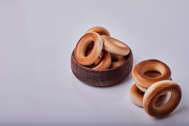 Cercle des craquelins ou des petits pains dans une tasse en bois isolé sur fond gris