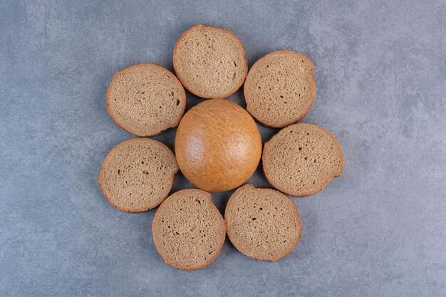 Cercle de tranches de pain brun autour d'un seul petit pain sur fond de marbre. photo de haute qualité