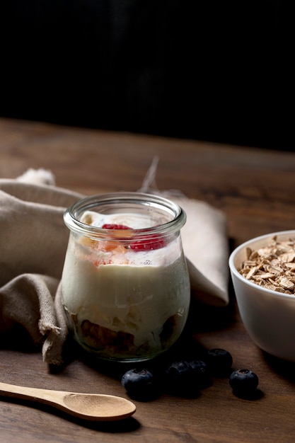 Photo gratuite céréales granola à angle élevé avec yougurt sur le bureau