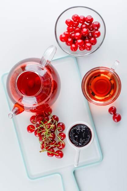 Cerise au thé, confiture dans un bol sur blanc et planche à découper, vue du dessus.