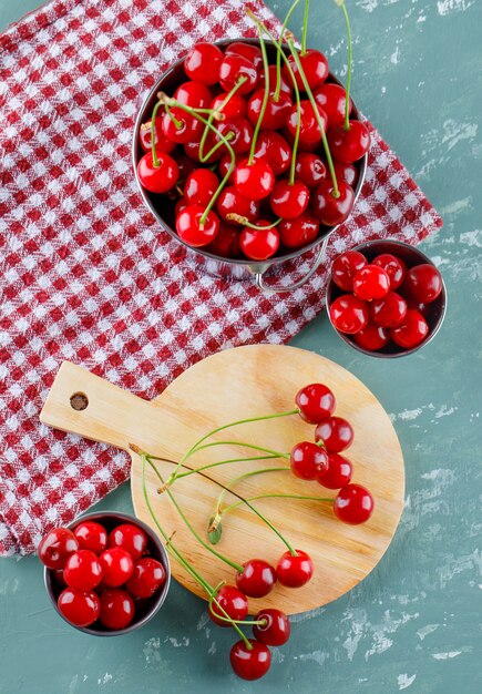 Cerise dans des seaux avec planche à découper à plat sur du plâtre et un torchon