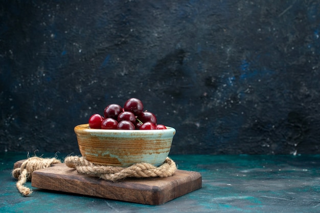 Cerises aigres fraîches à l'intérieur de la plaque avec des cordes sur dark