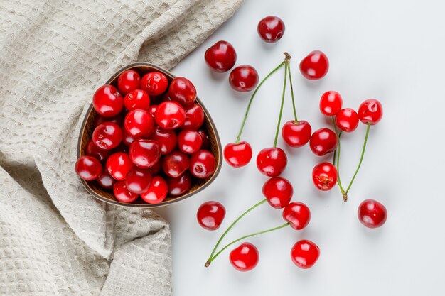 Cerises dans un bol sur blanc et torchon.