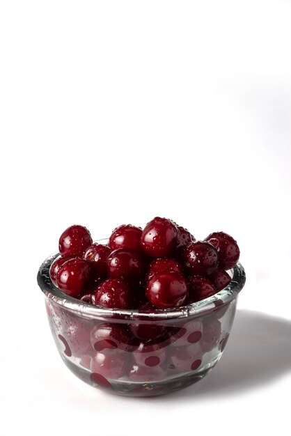 Cerises dans un bol en verre isolé sur blanc