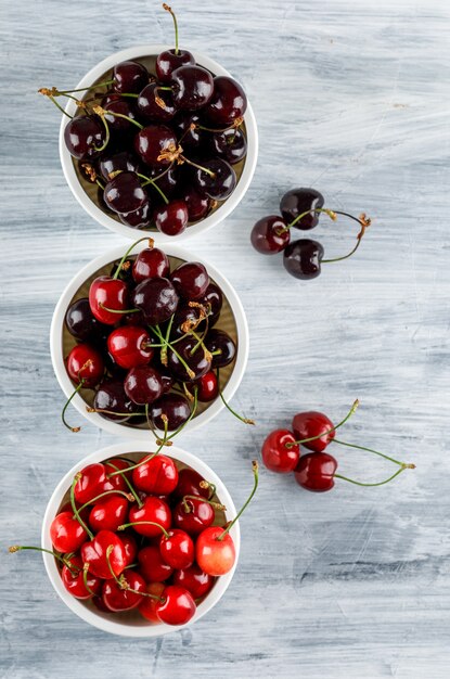 Cerises dans des bols à plat sur une surface grunge