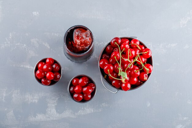 Cerises dans des seaux avec vue de dessus de jus