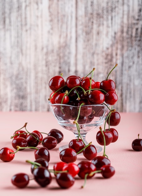 Cerises dans un vase sur une surface rose et grungy