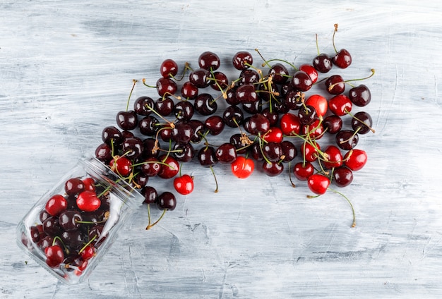 Cerises éparses d'un pot sur une surface grunge. vue de dessus.