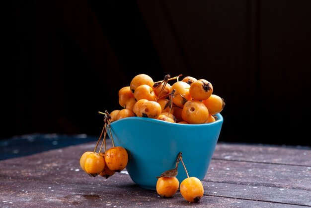 Cerises jaunes moelleuses fraîches et mûres à l'intérieur d'un bol bleu sur brown