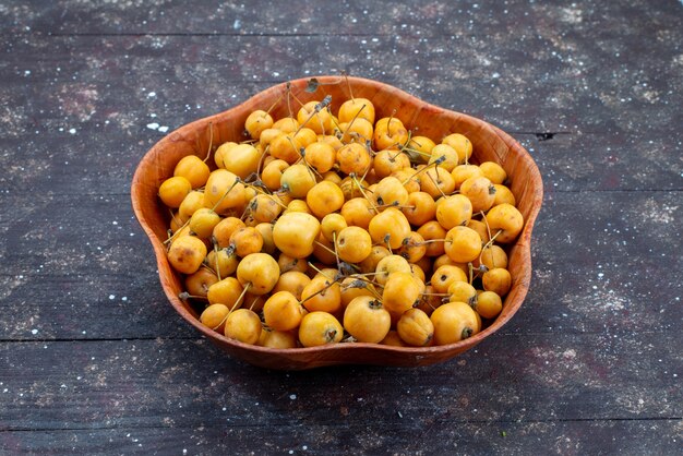 Cerises jaunes sucrées moelleuses et juteuses à l'intérieur de la plaque sur fond gris