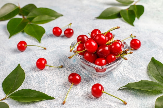 Cerises rouges dans un bol en verre transparent sur table grise