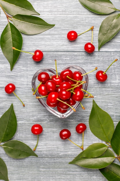 Cerises rouges dans un bol en verre transparent sur table grise