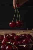 Photo gratuite cerises rouges à la main tirées de la plaque sur fond sombre