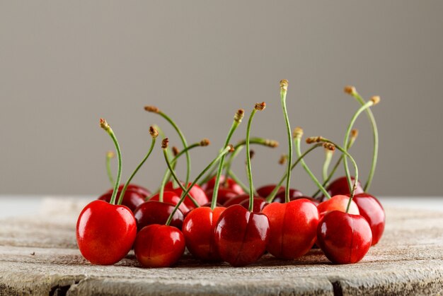 Cerises rouges sur une surface de planche grise et en bois. vue de côté.