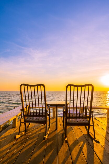 Chaise en bois vide et table au patio extérieur avec belle plage tropicale et la mer