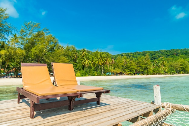 Chaise et lit sur une jetée en bois ou un pont avec plage tropicale et mer sur une île paradisiaque