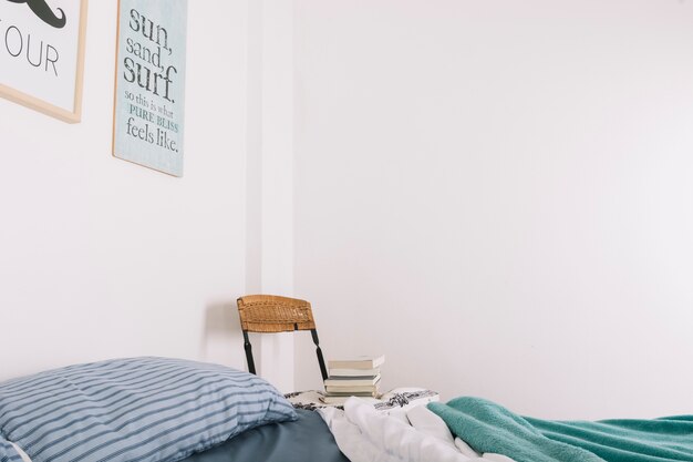 Chaise avec des livres debout près du lit