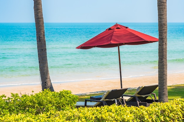 Chaise longue vide salon avec parasol autour de la plage mer océan ciel bleu pour les vacances de voyage de loisirs