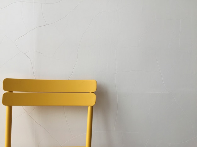 Chaise en plastique jaune contre un mur blanc