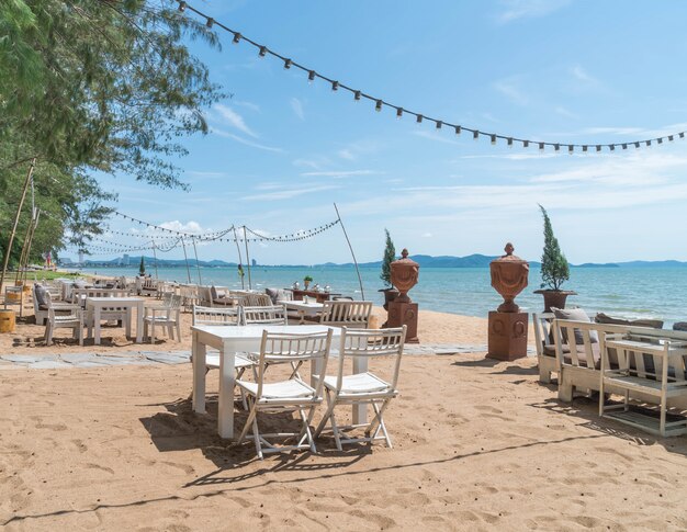 Chaises blanches et table sur la plage avec vue sur l&#39;océan bleu et le ciel clair