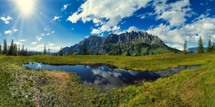 Photo gratuit champ d'herbe verte près du lac sous le ciel bleu et les nuages blancs pendant la journée