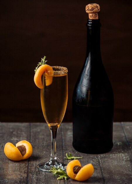 Champagne abricot en verre à champagne garni d'abricots sur un comptoir en bois